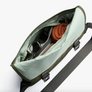 An open olive Classic Messenger Bag with a strap, shown on a white background with various items inside.