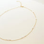 Gold necklace with small pearls on a beige background