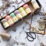 Box of colorful twine spools with a vintage-style advertisement and scissors on a textured surface.