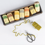 Collection of NUTSCHENE yarn spools in a box with a skein and scissors on a white background