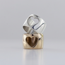 Two heart cut-out rings stacked, one polished silver and one yellow bronze, on a light gray background.