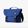 A indigo blue Classic Messenger Bag with black straps and buckles and top carrying handle. Photographed on white background.