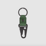 A keychain with a dark green textured leather tab and matte black metal components, including a split key ring and carabiner-style connector, shown on a light gray background.