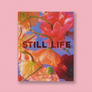 A hardcover book titled 'STILL LIFE' by Doan Ly, featuring a vibrant floral cover with orange, red, and pink flowers against a blue sky background, set against a solid pink backdrop.