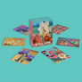 A boxed set of floral notecards titled "STILL LIFE" with several illustrated cards or prints arranged around it on a solid aqua background. The central package shows white flowers, pink blossoms, and fruit, while the surrounding pieces display additional floral and botanical artwork in different colors.