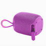 A purple portable Bluetooth speaker with a textured fabric grille, a matching purple carrying loop, and a small flip-up power adapter, shown on a plain white background.